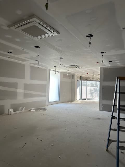 Ceiling cassette installed in a retail tenancy during fitout, shopfront glazing behind.
