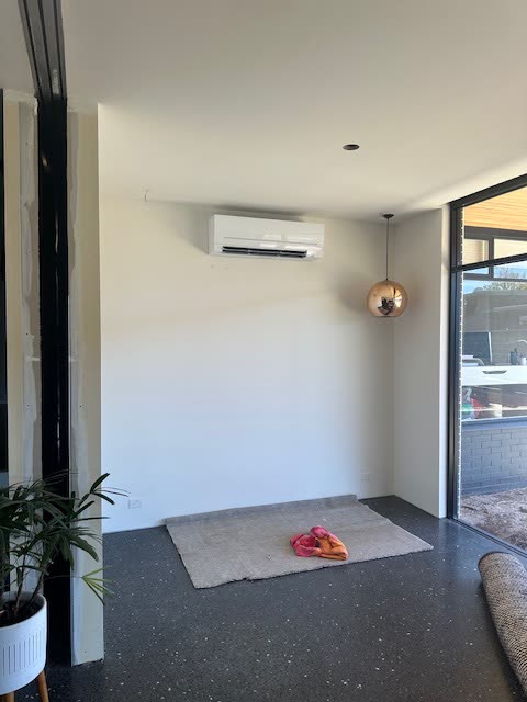 Room with polished concrete floors and a copper pendant light, ducted outlet in the ceiling.