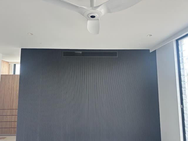 Linear slot diffuser set into a ceiling above a slatted timber feature wall.