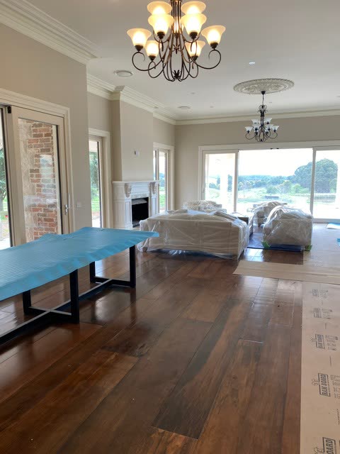 Living room with chandeliers and timber floors, ducted outlets set into the ceiling.