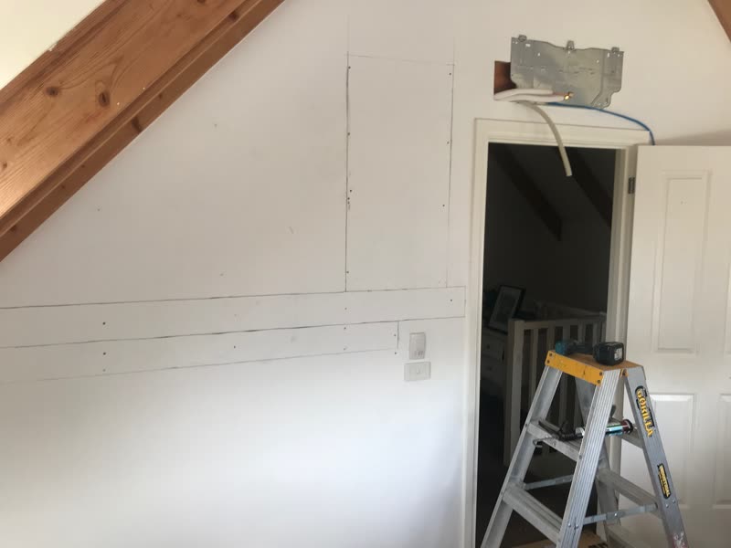The same wall patched and made good, with the bracket and conduit in place before the head unit goes on.