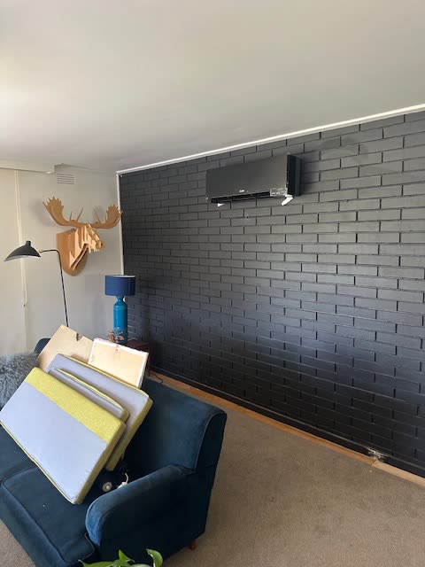 Split system head unit mounted on a dark brick interior wall.