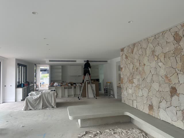 Interior with a stone feature wall and ducted outlets in the ceiling above.
