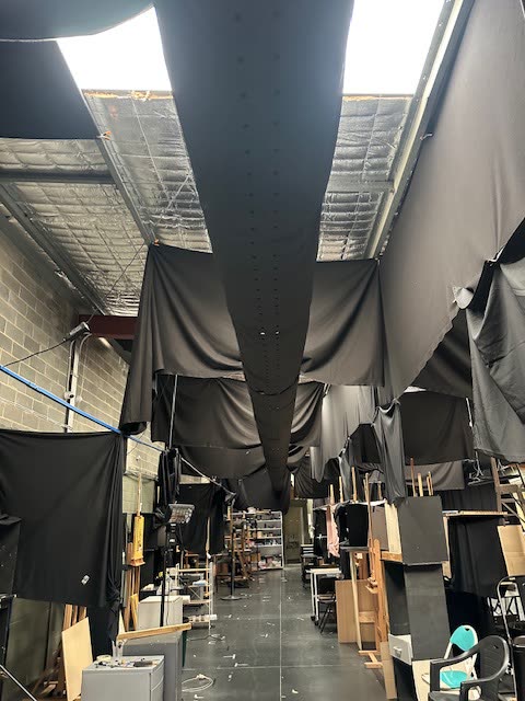 Large studio space with a long black fabric duct running the length of the ceiling.