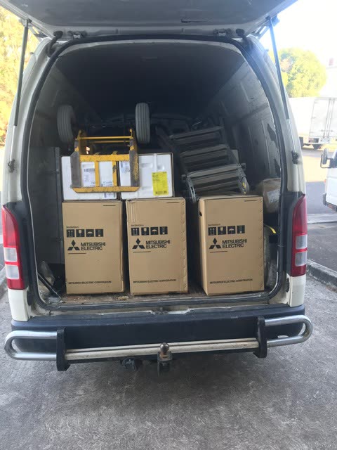 Three boxed Mitsubishi Electric units loaded in the back of the work van with a stair climbing trolley.