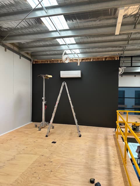 Split system head unit on a black feature wall in a converted warehouse with a mezzanine above.