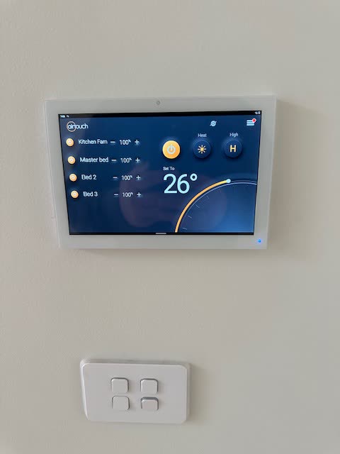 Wall mounted zone controller showing four named zones and a set temperature of 26 degrees.